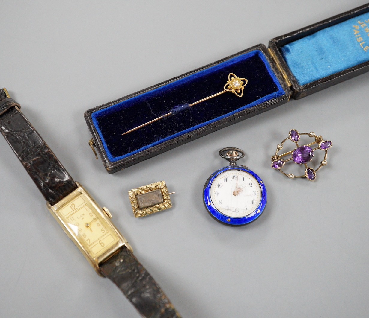 An early 20th century yellow metal, amethyst and seed pearl set oval brooch, 28mm, a Victorian yellow metal mourning brooch, a similar yellow metal and diamond set stick pin, a white metal and enamel fob watch(a.f.) and